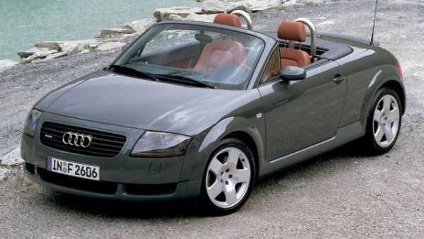 Калифорния, Сими Вали, 1994 г. Гласът на Джими Хендрикс отеква в стените на Audi Design Studio , докато дизайнерите Фрийман Томас и Питър Шрайер проследяват линии и изучават опростените едноместни автомобили на Auto Union от 30-те години на миналия век и минималистичните произведения на Баухаус стилистична философия. Така се ражда иконата на стила  -  TT, представен за първи път под формата на концептуална кола на автомобилното изложение във Франкфурт през 1995 г.  

Официално е пуснат в производство през октомври 1998 г. в случая на купето и август 1999 г. за роудстърите. Базиран на платформата PQ34 на Volkswagen Group, споделена с четвъртото поколение Audi A3 и Volkswagen Golf, той дебютира с автоматичната трансмисия с двоен съединител DSG и спомогна за допълнителното укрепване на имиджа на маркатав премиум сегмента. 

Два двигателя предлага първото поколение - 1.8 четирицилиндров с диапазон на мощността от 150 к.с. за началното ниво до 240 за TT Quattro Sport и &bdquo; VR6 &ldquo; с 3,2 литра работен обем и 250 к.с. Последният е комбиниран стандартно със задвижване на четирите колела със съединител Haldex. Между 1999 и 2006 г. са произведени  90 733 Audi TT Roadster , към които се добавят по-често срещаните Coup&eacute;, продадени в тираж от 178 765 бройки. 